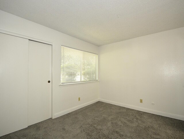 4779 N Cedar Ave # 109, Fresno, CA 93726 - unfurnished bedroom with dark carpet, a closet, a textured ceiling, and baseboards