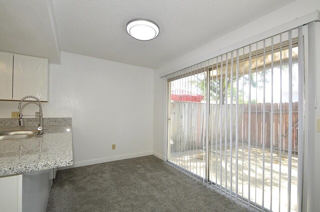 4779 N Cedar Ave # 109, Fresno, CA 93726 - unfurnished dining area with a sink, carpet flooring, baseboards, and a textured ceiling