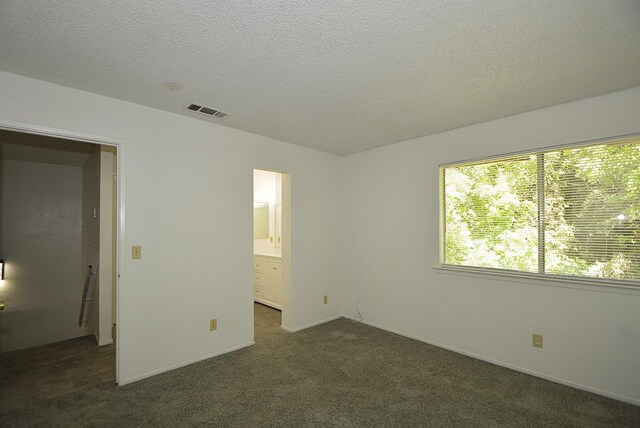 4779 N Cedar Ave # 109, Fresno, CA 93726 - unfurnished bedroom with dark colored carpet, a textured ceiling, and connected bathroom