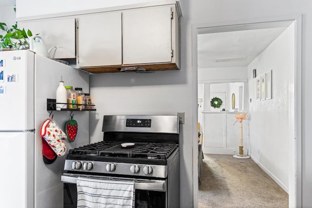 1586 N Calaveras St, Fresno, CA 93728 - kitchen with stainless steel range with gas cooktop, carpet flooring, white cabinets, baseboards, and freestanding refrigerator