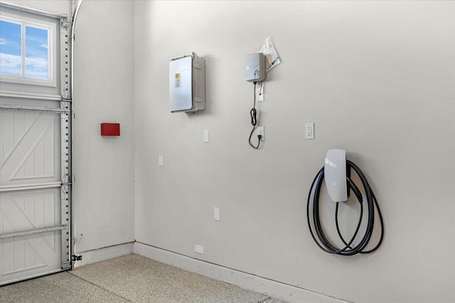 11753 N Turf Dr, Fresno, CA 93730 - garage view of car charger, baseboards, and speckled floor