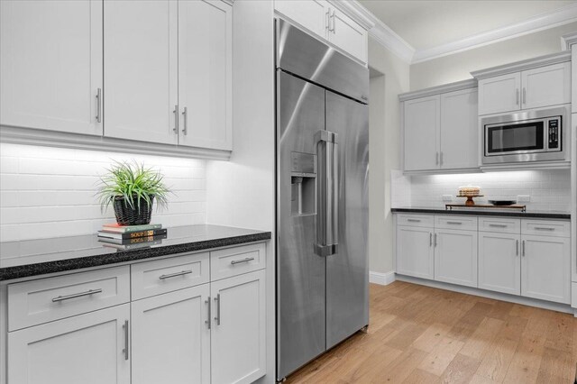 11753 N Turf Dr, Fresno, CA 93730 - kitchen with stainless steel appliances, ornamental molding, light wood-style flooring, backsplash, and dark stone counters