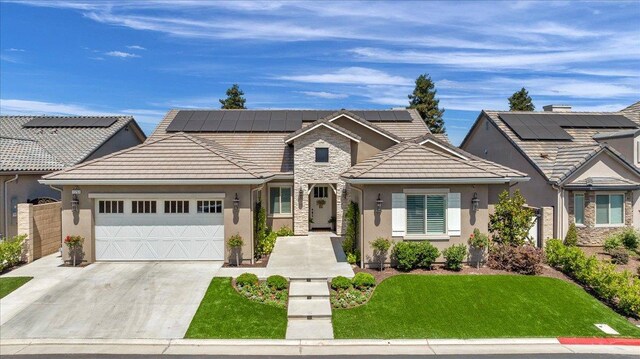 11753 N Turf Dr, Fresno, CA 93730 - view of front of house with stucco siding, a garage, driveway, stone siding, and solar panels