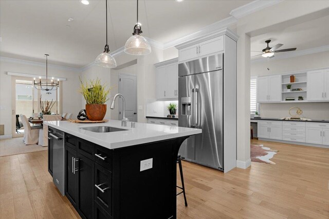 11753 N Turf Dr, Fresno, CA 93730 - kitchen with high end fridge, a sink, dark cabinetry, light wood finished floors, and ornamental molding