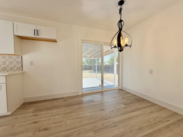 1310 Fresno St, Madera, CA 93638 - unfurnished dining area with light wood-type flooring, a chandelier, and baseboards