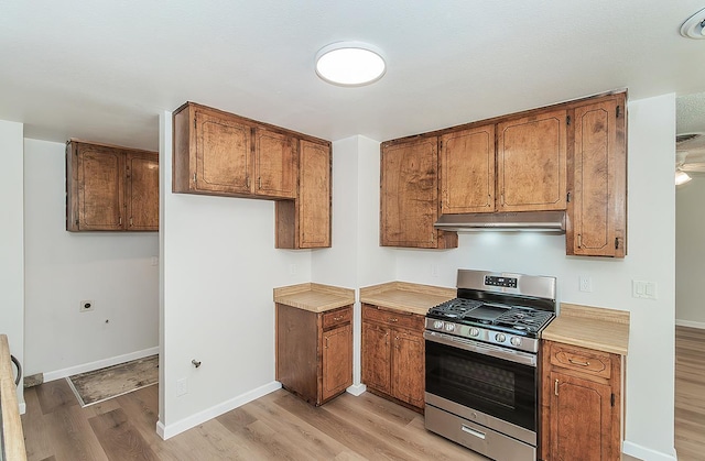 709 Keith St, Lemoore, CA 93245 - kitchen featuring stainless steel gas range oven, light wood-style floors, under cabinet range hood, brown cabinetry, and light countertops