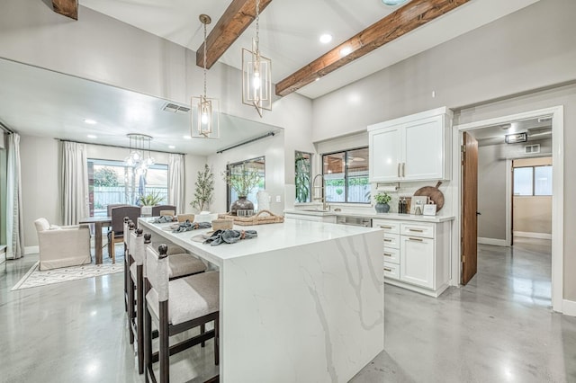 3841 W Alluvial Ave, Fresno, CA 93711 - kitchen featuring concrete flooring, white cabinetry, beamed ceiling, a kitchen bar, and a sink