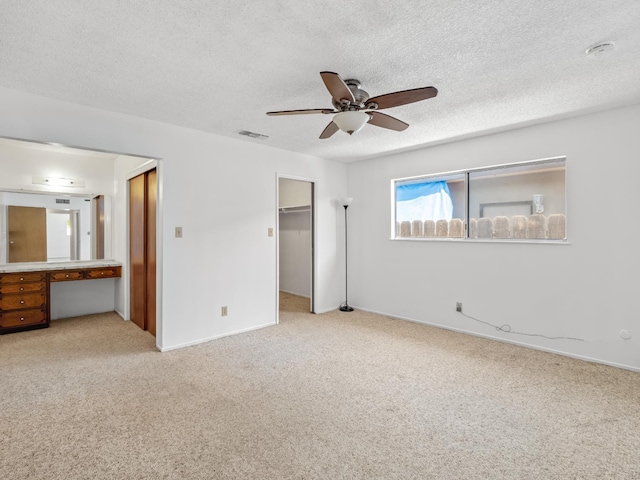 6413 N 5th St, Fresno, CA 93710 - unfurnished bedroom featuring carpet floors, baseboards, a walk in closet, a textured ceiling, and a ceiling fan