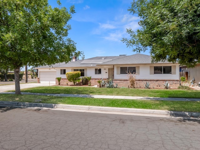 6413 N 5th St, Fresno, CA 93710 - ranch-style house featuring brick siding, concrete driveway, a garage, and roof mounted solar panels