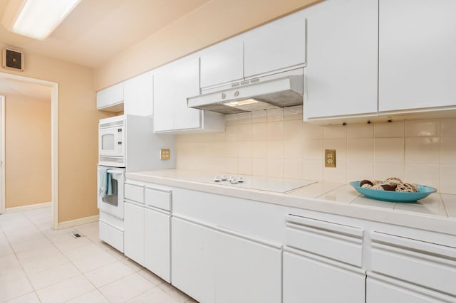 5835 E Hamilton Ave, Fresno, CA 93727 - kitchen featuring under cabinet range hood, light countertops, white cabinets, and backsplash