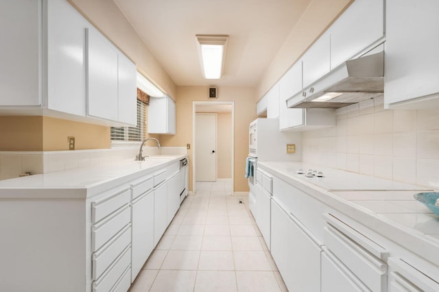 5835 E Hamilton Ave, Fresno, CA 93727 - kitchen featuring stovetop, tasteful backsplash, a sink, under cabinet range hood, and white cabinetry