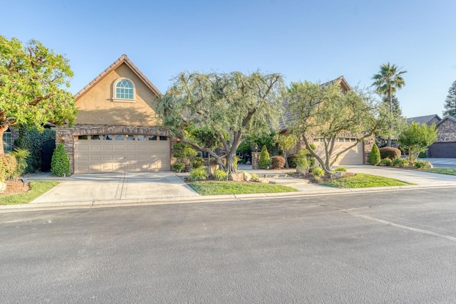 1223 E Rosemont Ln, Fresno, CA 93730 - view of property hidden behind natural elements featuring driveway, stucco siding, and an attached garage