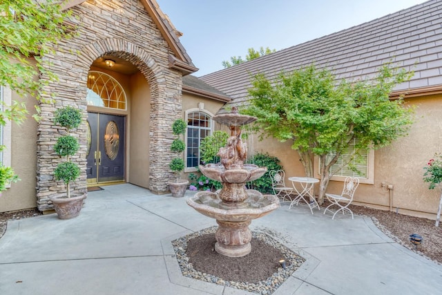 1223 E Rosemont Ln, Fresno, CA 93730 - view of exterior entry with stone siding, a patio, and stucco siding