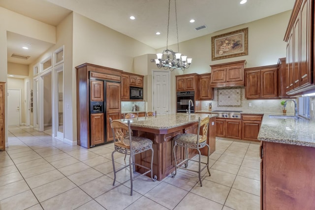 1223 E Rosemont Ln, Fresno, CA 93730 - kitchen featuring black appliances, a sink, a center island with sink, light tile patterned floors, and a kitchen bar
