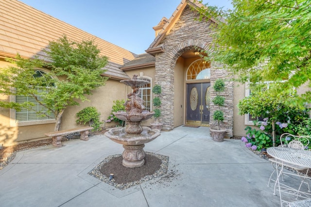 1223 E Rosemont Ln, Fresno, CA 93730 - view of exterior entry featuring a patio, stone siding, and stucco siding