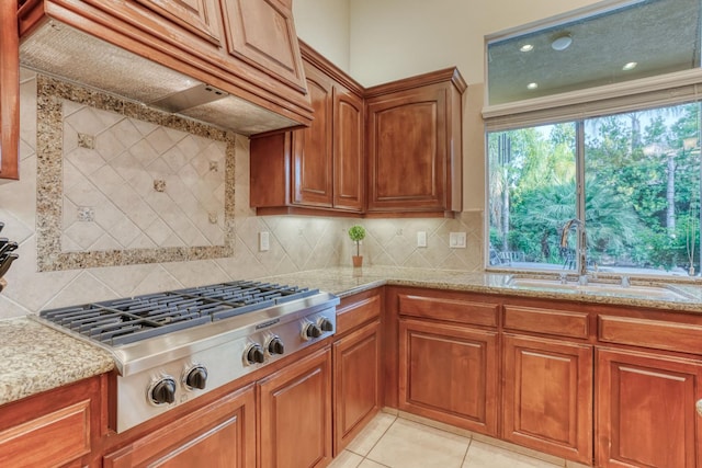 1223 E Rosemont Ln, Fresno, CA 93730 - kitchen featuring a sink, brown cabinets, stainless steel gas cooktop, custom range hood, and light stone counters