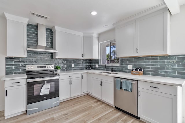 3678 N 7th St, Fresno, CA 93726 - kitchen featuring stainless steel appliances, wall chimney range hood, a sink, light countertops, and white cabinets