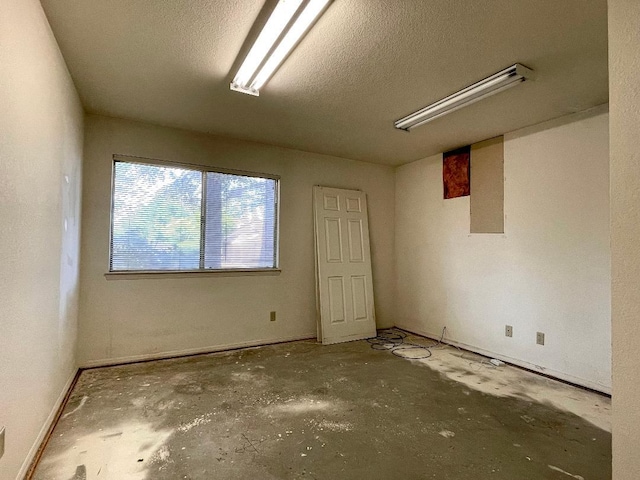 5092 W Stuart Ave, Fresno, CA 93722 - empty room featuring concrete floors, a textured ceiling, and baseboards