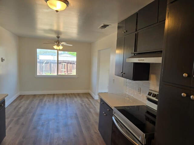 2018 E Pico Ave, Fresno, CA 93726 - kitchen with stainless steel electric stove, under cabinet range hood, wood finished floors, baseboards, and tasteful backsplash
