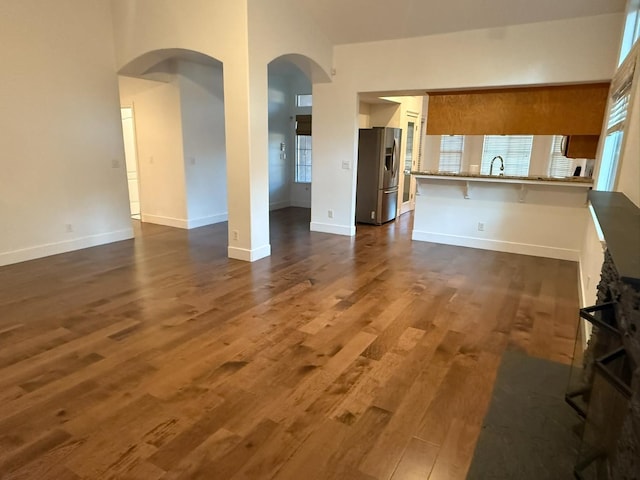 9850 N Winery Ave, Fresno, CA 93720 - unfurnished living room with arched walkways, dark wood-type flooring, baseboards, and a sink