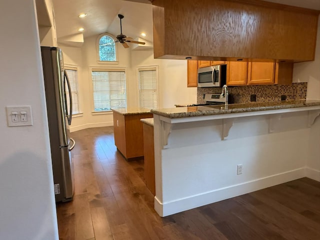 9850 N Winery Ave, Fresno, CA 93720 - kitchen featuring appliances with stainless steel finishes, a peninsula, dark wood-type flooring, a ceiling fan, and brown cabinets