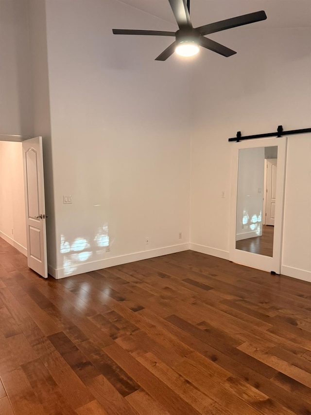 9850 N Winery Ave, Fresno, CA 93720 - spare room with dark wood-style flooring, a ceiling fan, a towering ceiling, baseboards, and a barn door