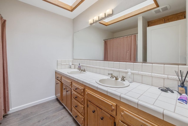 300 W Adrian Way, Hanford, CA 93230 - full bathroom featuring double vanity, wood finished floors, decorative backsplash, baseboards, and a skylight