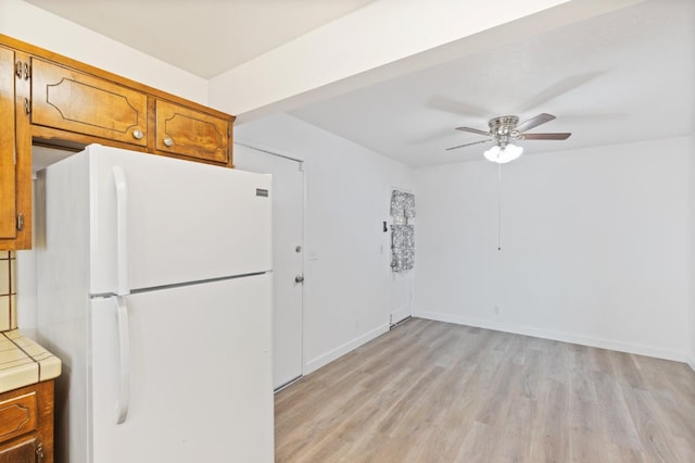 4003 E El Monte Way, Fresno, CA 93702 - kitchen featuring freestanding refrigerator, brown cabinetry, tile countertops, light wood-type flooring, and a ceiling fan
