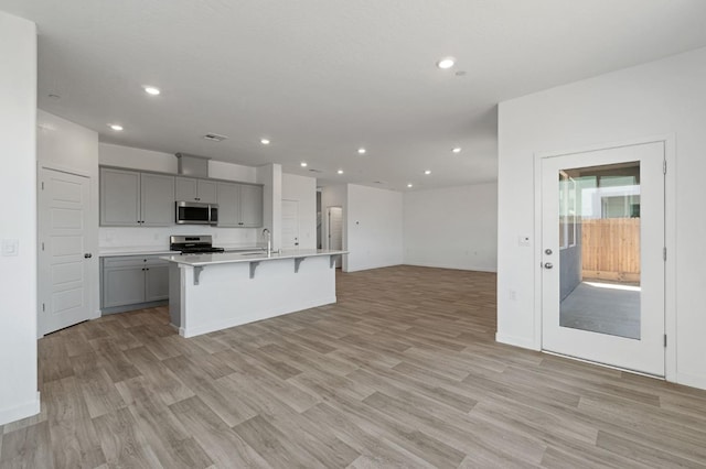 3210 Frontera Ave, Clovis, CA 93619 - kitchen featuring stainless steel appliances, gray cabinetry, open floor plan, a breakfast bar area, and an island with sink