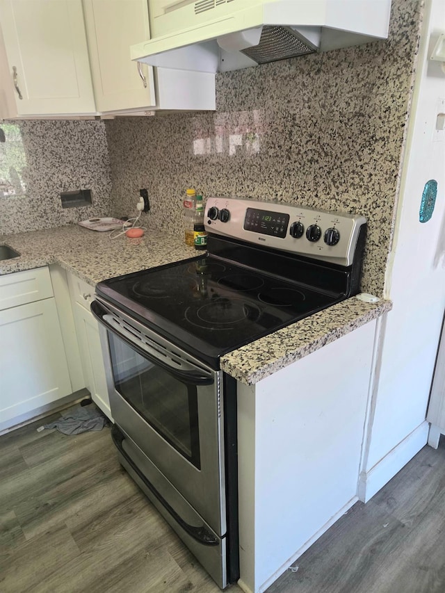 4531 E Fedora Ave, Fresno, CA 93726 - kitchen with stainless steel electric range oven, custom exhaust hood, wood finished floors, white cabinets, and tasteful backsplash