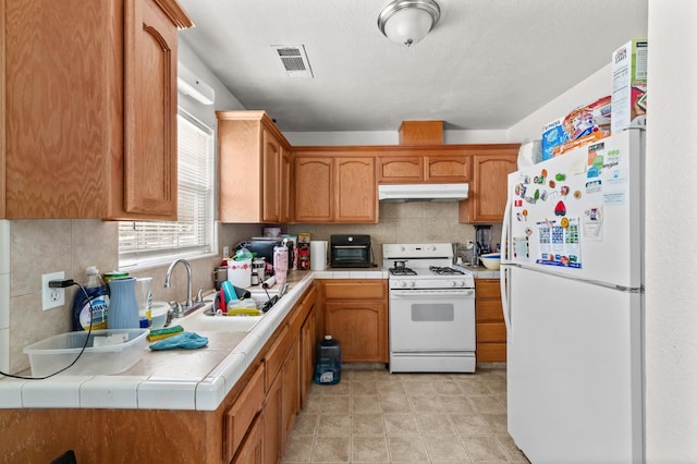 1808 Jenning St, Mendota, CA 93640 - kitchen with white appliances, under cabinet range hood, tile countertops, decorative backsplash, and a sink