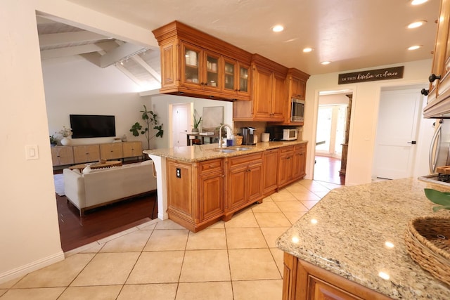 2210 W Spruce Ave, Fresno, CA 93711 - kitchen featuring a sink, brown cabinetry, light stone counters, light tile patterned flooring, and a peninsula