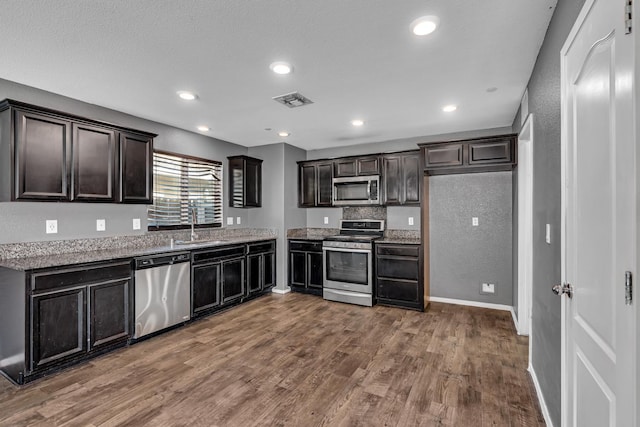 5576 E Burns Ave, Fresno, CA 93727 - kitchen with appliances with stainless steel finishes, a sink, wood finished floors, stone counters, and recessed lighting