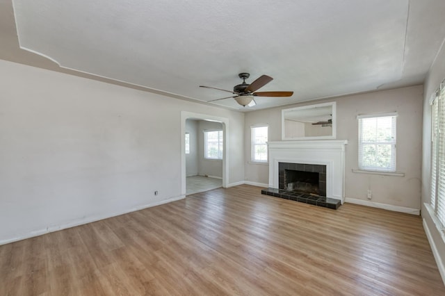 724 W Harvard Ave, Fresno, CA 93705 - unfurnished living room with a ceiling fan, light wood finished floors, a tiled fireplace, and baseboards