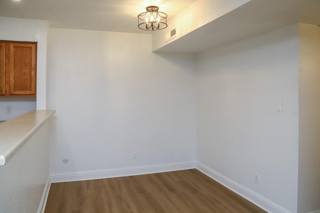 2881 E Huntington Blvd Unit 230, Fresno, CA 93721 - unfurnished dining area with dark wood finished floors, baseboards, and a chandelier