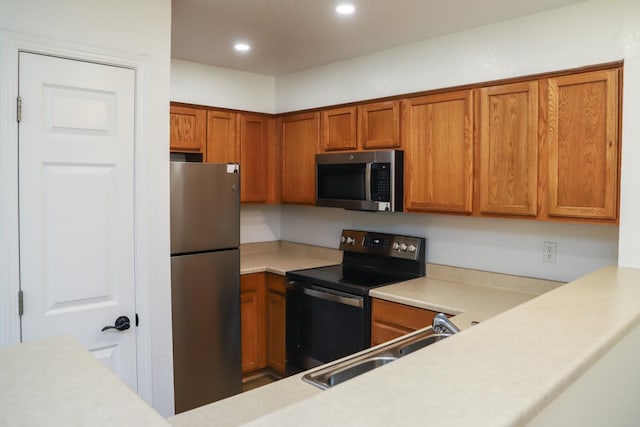 2881 E Huntington Blvd Unit 230, Fresno, CA 93721 - kitchen with appliances with stainless steel finishes, a sink, light countertops, brown cabinetry, and recessed lighting