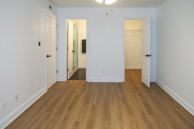 2881 E Huntington Blvd Unit 230, Fresno, CA 93721 - unfurnished bedroom with a walk in closet, wood finished floors, a closet, and baseboards