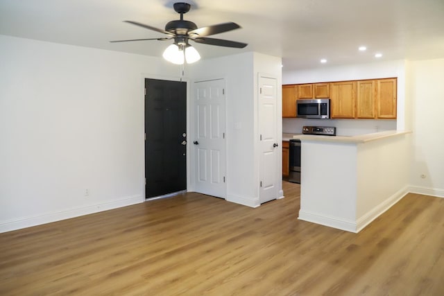 2881 E Huntington Blvd Unit 230, Fresno, CA 93721 - kitchen with stainless steel microwave, baseboards, electric range, light wood-style floors, and a peninsula