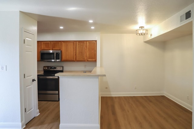 2881 E Huntington Blvd Unit 230, Fresno, CA 93721 - kitchen featuring appliances with stainless steel finishes, wood finished floors, brown cabinetry, light countertops, and baseboards
