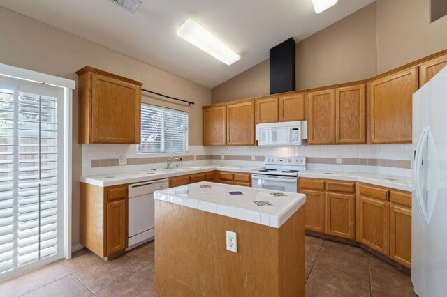 2841 E Brandon Ln, Fresno, CA 93720 - kitchen with white appliances, vaulted ceiling, backsplash, tile countertops, and light tile patterned floors