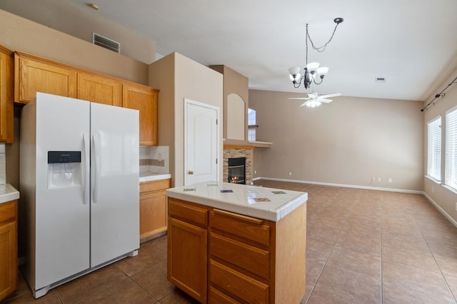 2841 E Brandon Ln, Fresno, CA 93720 - kitchen featuring white refrigerator with ice dispenser, a chandelier, light tile patterned floors, a glass covered fireplace, and decorative backsplash