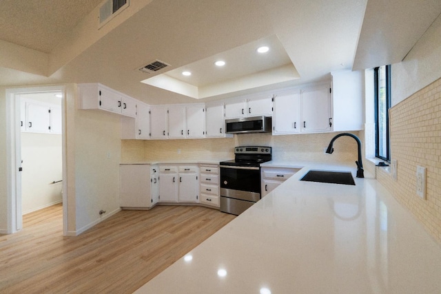 1707 Douglas Ave, Clovis, CA 93611 - kitchen with stainless steel appliances, a sink, light wood-type flooring, a tray ceiling, and white cabinetry