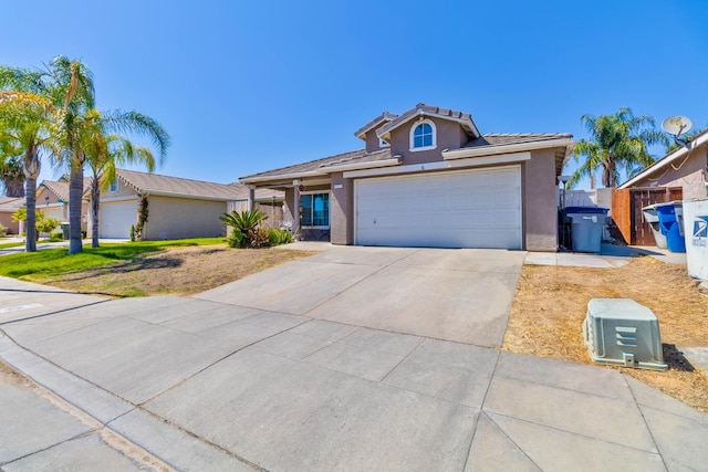 5572 W Indianapolis Ave, Fresno, CA 93722 - view of front of house with stucco siding, driveway, a tile roof, and a garage