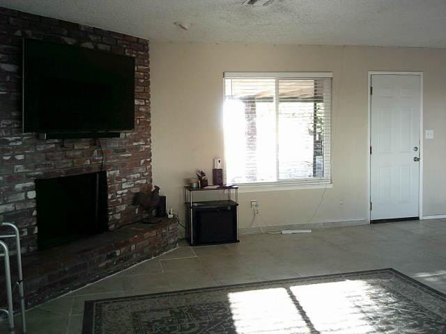 582 N Academy Ave, Sanger, CA 93657 - unfurnished living room with a brick fireplace, tile patterned floors, and baseboards