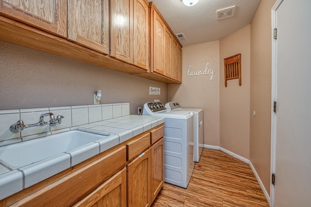 41228 Heartwood Ln, Shaver Lake, CA 93664 - washroom with cabinet space, light wood-style floors, separate washer and dryer, baseboards, and a textured ceiling
