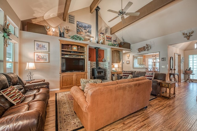 41228 Heartwood Ln, Shaver Lake, CA 93664 - living area with a wood stove, light wood-style flooring, high vaulted ceiling, a ceiling fan, and beam ceiling