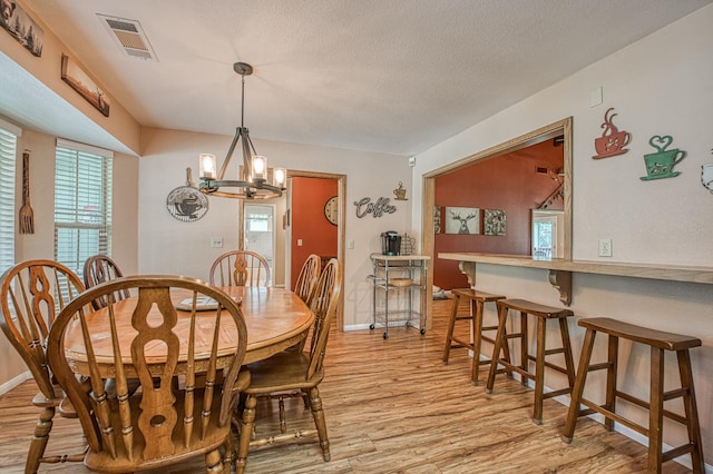 41228 Heartwood Ln, Shaver Lake, CA 93664 - dining space featuring light wood-style flooring, a chandelier, baseboards, and a textured ceiling