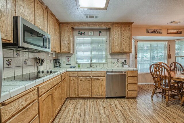 41228 Heartwood Ln, Shaver Lake, CA 93664 - kitchen with appliances with stainless steel finishes, a sink, light wood finished floors, healthy amount of natural light, and a textured ceiling