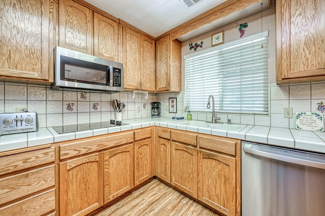41228 Heartwood Ln, Shaver Lake, CA 93664 - kitchen with appliances with stainless steel finishes, a sink, tasteful backsplash, and light wood-type flooring