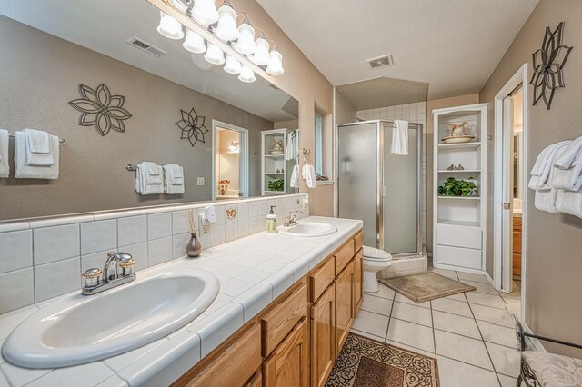 41228 Heartwood Ln, Shaver Lake, CA 93664 - bathroom featuring a stall shower, double vanity, tile patterned floors, toilet, and backsplash
